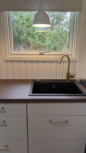 a kitchen with a sink and a window at Henneby Camping - hytter in Henne Strand