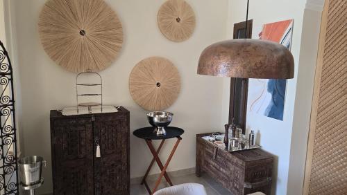 a room with a lamp and some wooden plates on the wall at Villa AIMA - avec Gourvernante in Douar Soukkane