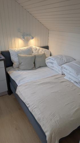 a large bed with white sheets and pillows at Henneby Camping - hytter in Henne Strand