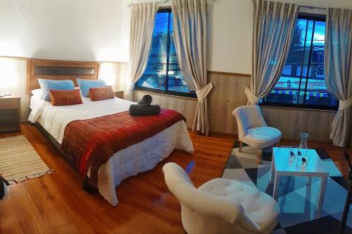 a bedroom with a bed and two chairs at Hotel y Cabañas La Magia del Sur in Valdivia