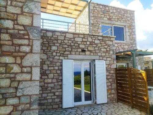 a stone house with a sliding glass door at Stone Bay Houses in Messinia Kalamaki Beach Area in Chrani