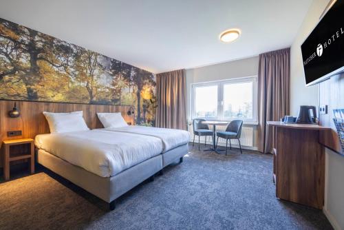 a hotel room with a large bed and a table at Fletcher Hotel-Restaurant Paasberg in Lochem