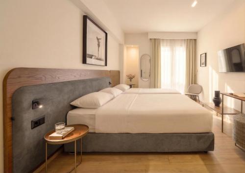a hotel room with a large bed and a table at Pillow by the Sea in Thessaloniki