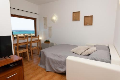 a bedroom with a bed and a television and a table at L10 Terrazza Ponente A breathtaking view in Stintino