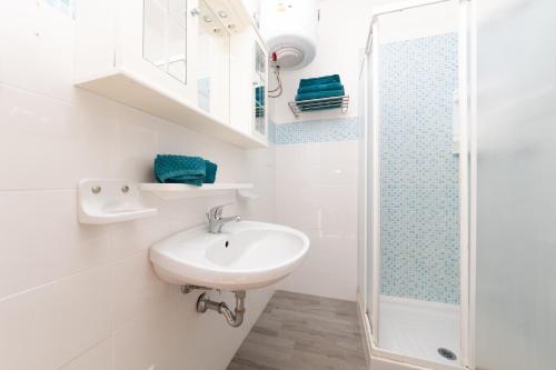 a white bathroom with a sink and a shower at L10 Terrazza Ponente A breathtaking view in Stintino