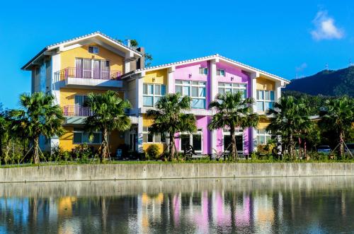 a pink and yellow building next to a body of water at 光腳丫宜蘭民宿 in Dongshan