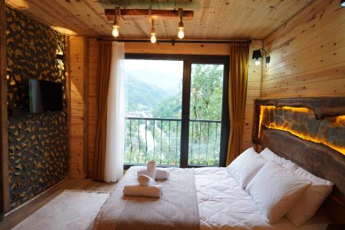 a bedroom with a bed with a large window at Perla garden suit in Çamlıhemşin