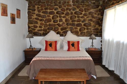 a bedroom with a bed and a stone wall at Mokoya Lodge in Hekpoort