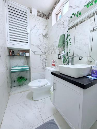 a white bathroom with a sink and a toilet at MARLIN TURQUESA DEPARTAMENTOs FRENTE AL MAR in Cancún