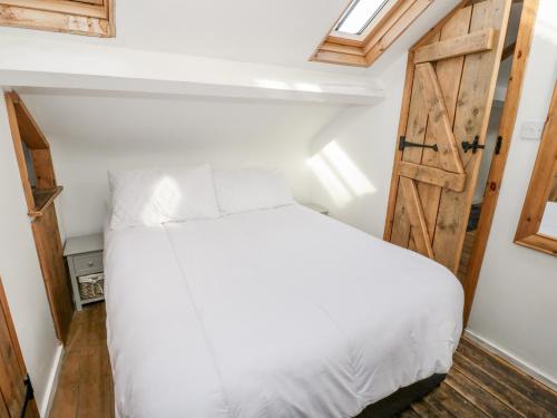 a bedroom with a white bed and a wooden door at Studio Bach in Beaumaris