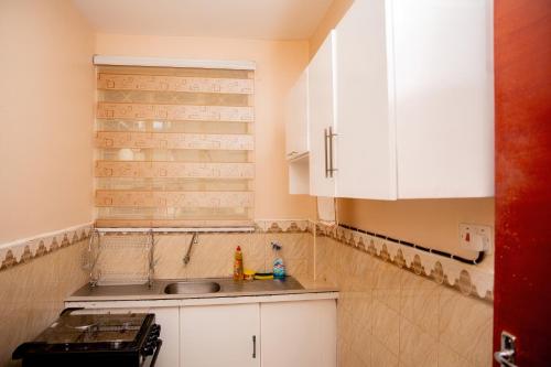a kitchen with white cabinets and a sink at Chuma's home in Arusha