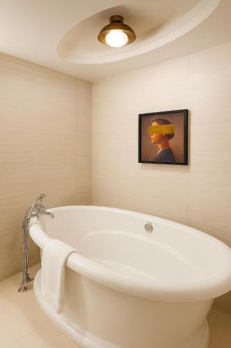 a white bath tub in a bathroom with a picture at Metcalfe Hotel Montréal by Gray Collection in Montreal