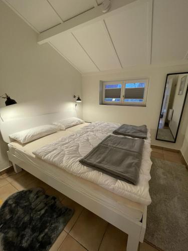 a white bed in a room with a mirror at Cozy Beach Home in De Haan