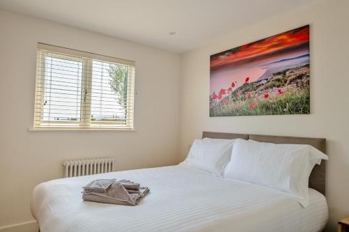 a bedroom with a white bed with a painting on the wall at 3 Bed in Adgestone oc-a32613 in Brading