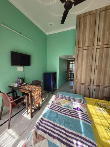 a bedroom with a bed and a table and a tv at Nature View Homestay in Dehradun