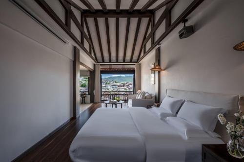 a bedroom with a white bed and a living room at Maison lyly 300 Year Historical Cultural Courtyard and Ancient City View in Lijiang