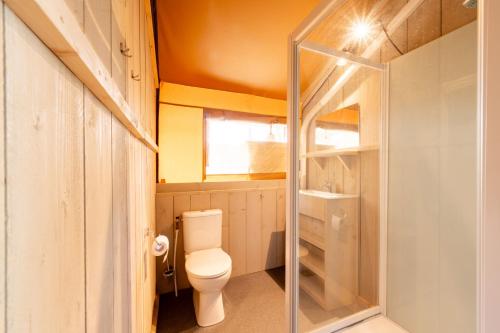 a bathroom with a toilet and a glass door at Glamping Saint Germain in Saint-Germain-du-Bel-Air