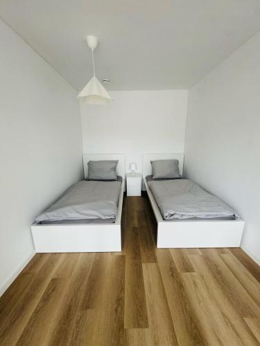 two beds in a room with white walls and wooden floors at Siegen Apartments - Modern & mit Parkplatz in Siegen