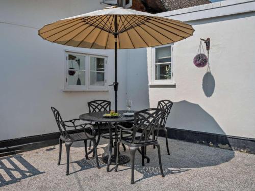 a table and chairs under an umbrella on a patio at 2 Bed in Romsey oc-thatc in Newtown