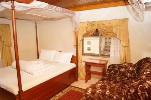 Un dormitorio con una cama con dosel y una silla. en Vision Hotel Kampala, en Kampala