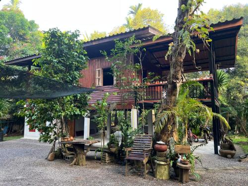 a house with a balcony and a tree at Ban Suan Chana Homestay in Ban Pha Saeng Lang