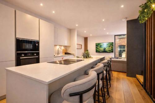a kitchen with a large island with bar stools at West Townhouse by CasaCity in Manchester