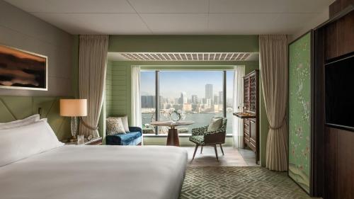 a bedroom with a bed and a view of the city at Mandarin Oriental, Hong Kong in Hong Kong
