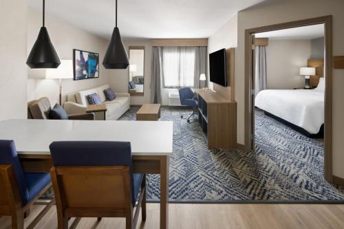 a hotel room with a bed and a living room at Candlewood Williamsport by IHG in Williamsport