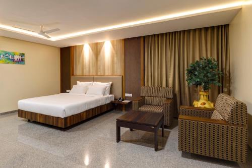 a hotel room with a bed and a chair at Hotel Silver Oak 7 Minutes Walk to Mahalaxmi Temple in Kolhapur