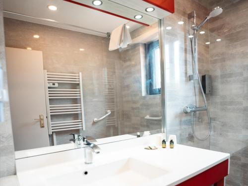 a bathroom with a sink and a shower and a mirror at Hotel Restaurant Au Parc des Cigognes in Kintzheim