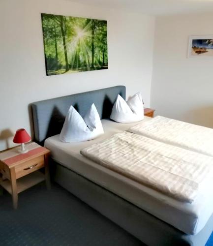 a bedroom with a bed with white sheets and a table at Pension Villa Sophia in Sassnitz