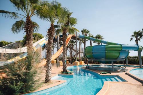 a water slide at a resort with palm trees at BLUESEA Marina Parc in Na Macaret