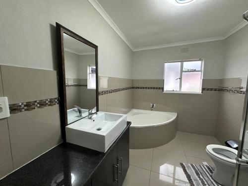 a bathroom with a sink and a tub and a toilet at Phela Guesthouse in Edenvale