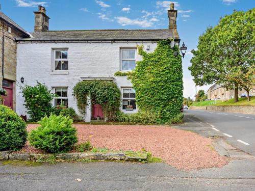 a white house with ivy on the side of a road at 4 Bed in Rothbury oc-cn180 in Rothbury