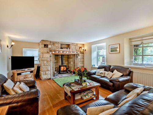 a living room with leather furniture and a stone fireplace at 4 Bed in Rothbury oc-cn180 in Rothbury