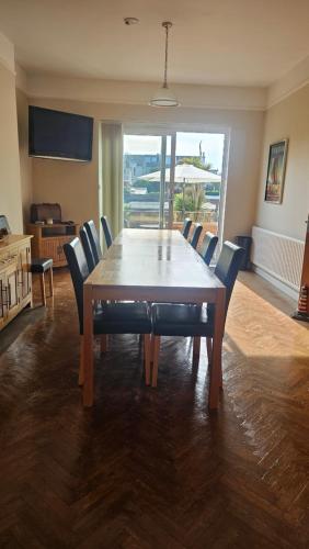 a large dining room table with chairs and a large window at Clinmore House in Paignton