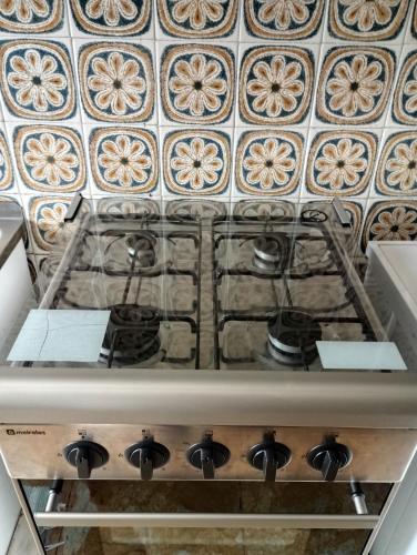 a stove top in a kitchen with a tile wall at Casa de alojamento local (T2) Queluz de Baixo in Oeiras