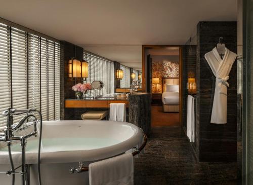a bathroom with a bath tub and a bedroom at Mandarin Oriental, Hong Kong in Hong Kong