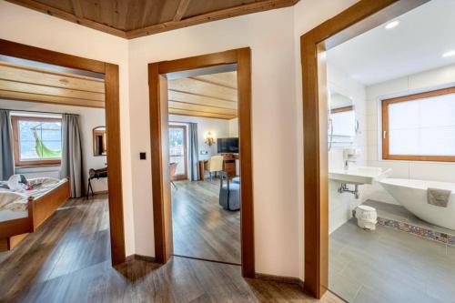 a bathroom with a large mirror and a tub and a sink at ALPENHOTEL TYROL - B&B - ADULTS ONLY - Alpines Lifestylehotel mit NaturSPA & Wellness in Pertisau