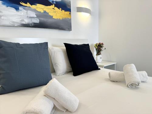 a white bed with black and white pillows at Central Suites Aegina 3 in Egina
