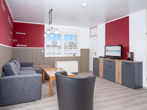 a living room with a couch and a tv at Holiday Home Gila by Interhome in Dornumersiel