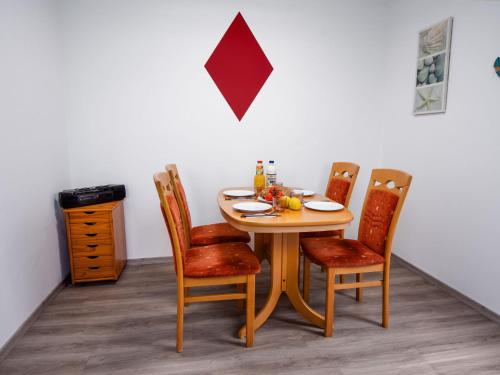 a dining room table with four chairs and a table with fruit on it at Holiday Home Gila by Interhome in Dornumersiel