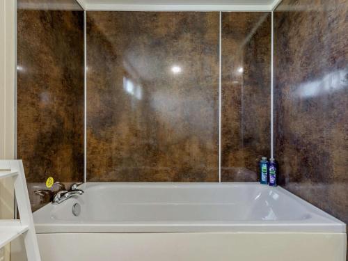 a bath tub in a bathroom with a brown wall at 2 Bed in Sowerby Bridge oc-90887 in Sowerby Bridge