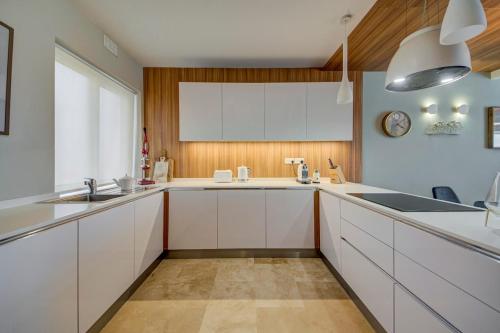 a large kitchen with white cabinets and a sink at Vista Laguna - Harbour View - Private Jacuzzi in Għajnsielem