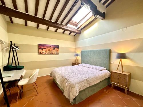 a bedroom with a bed and a desk and a window at Galli Tassi Suite in Lucca