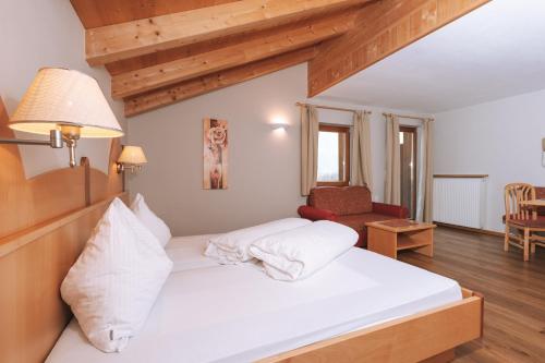 a bedroom with a white bed and a chair at Residence Fallrohrhof in Naturno
