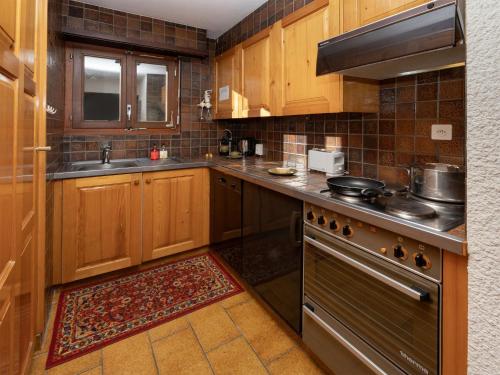 a kitchen with wooden cabinets and a stove top oven at Apartment Centaure B RI 1 by Interhome in Ovronnaz