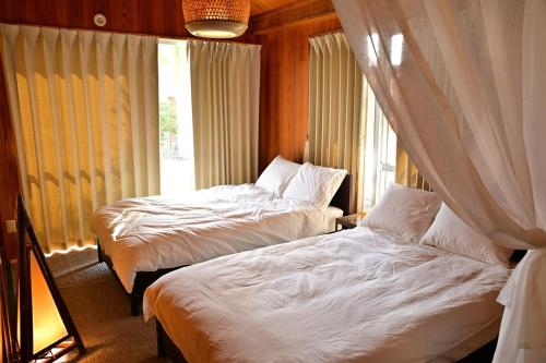 two beds in a room with a window at 南国リゾート Bari Okinawa 連泊宿泊限定価格 in Itoman