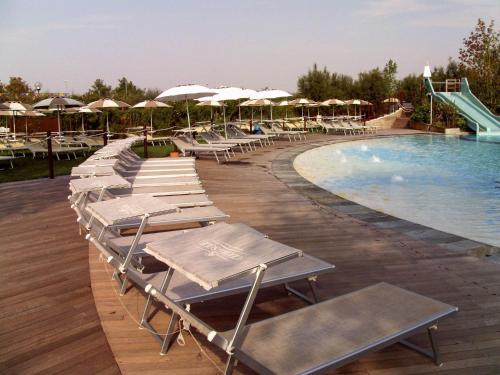 a row of lounge chairs next to a swimming pool at Glamping Lido di Spina in Lido di Spina