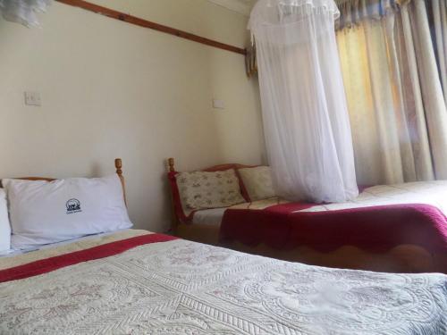 a bedroom with two beds and a window with curtains at Rhino Motel Mbarara in Mbarara